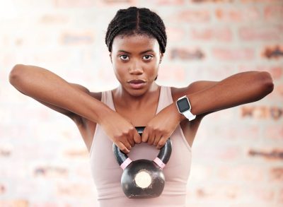 woman lifting kettlebell, concept of how often to do strength training to get lean