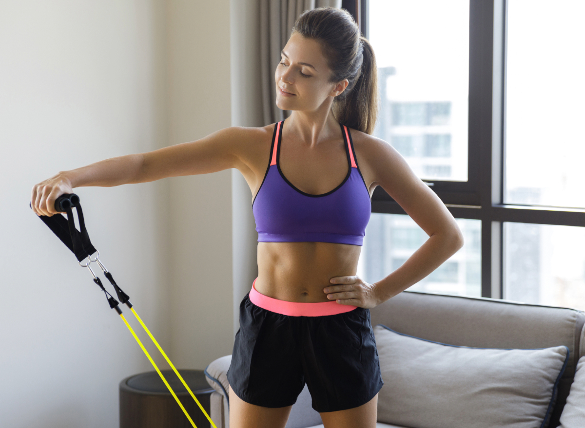 woman doing resistance band exercise, concept of at-home strength workouts for women to lose weight