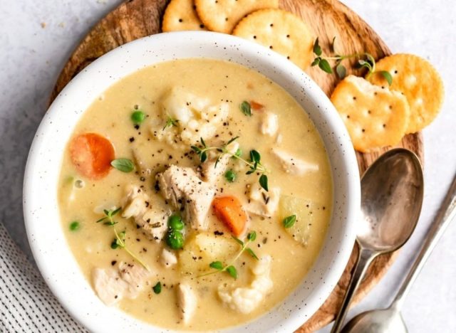 bowl of soup on a table with crackers and spoon