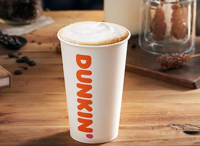 Cup of Dunkin' cappuccino on top of wooden table