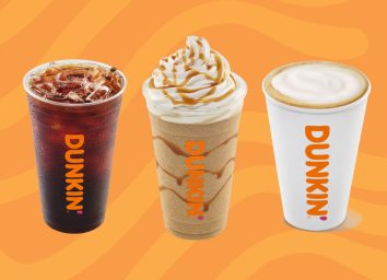 three cups of Dunkin' drinks on an orange background