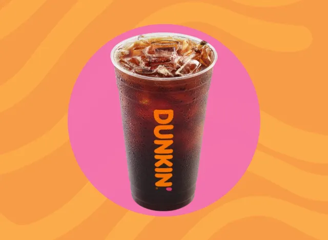 cup of Dunkin' cold brew on a pink and orange background