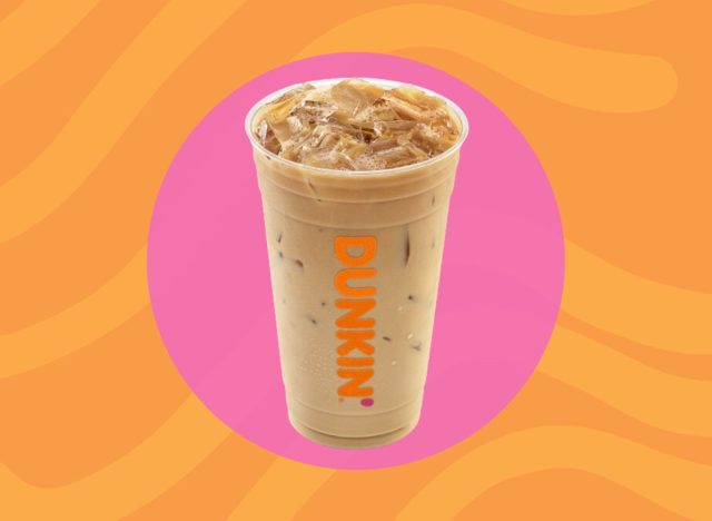 Cup of Dunkin' iced coffee on a pink and orange background.