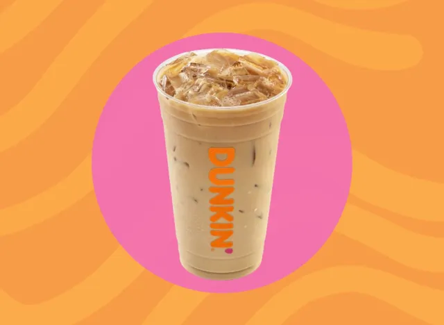 Cup of Dunkin' iced coffee on a pink and orange background.