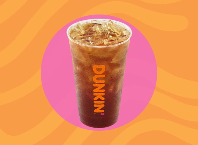 cup of Dunkin' iced teaon a pink and orange background.