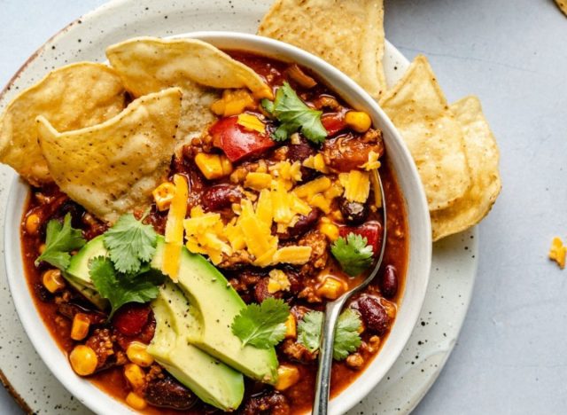 bowl of turkey chili with cheese, vegetables, beans, and chips on top