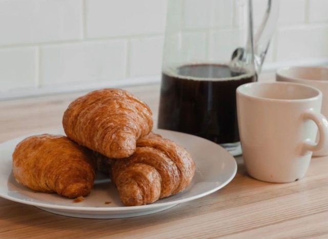 plate of croissants next to coffee and mugs