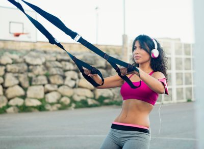 fitness woman doing TRX rows outdoors, concept of stability exercises to build strength