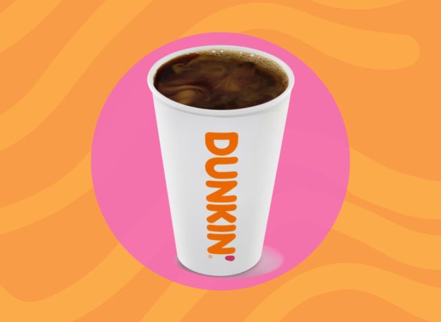 cup of Dunkin' hot coffee on a pink and orange background