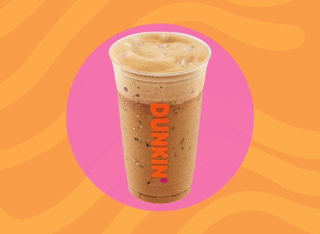 Dunkin iced cappuccino on a pink and orange background.
