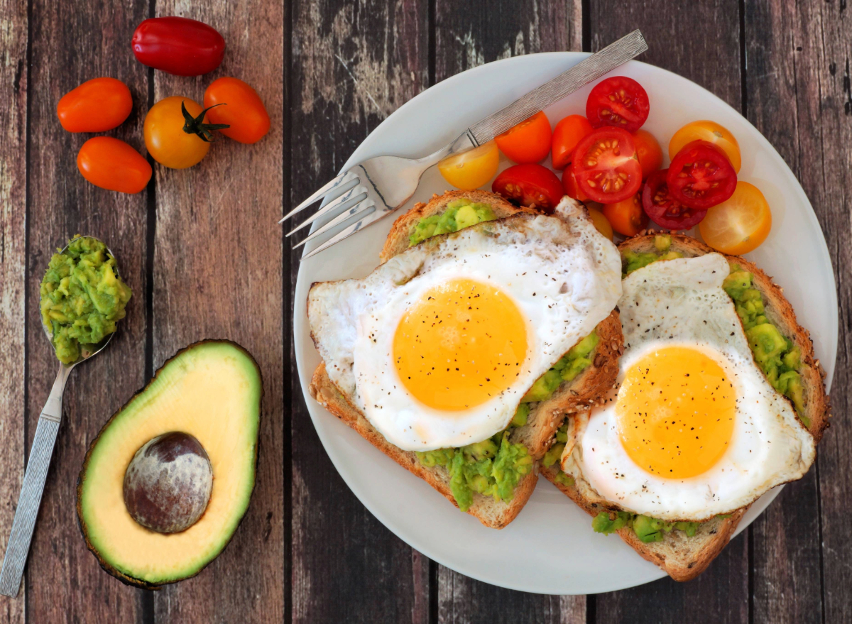 eggs on avocado toast with baby tomatoes, concept of what eating eggs does to your waistline