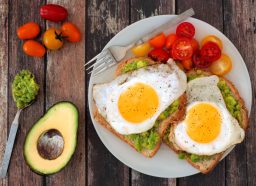 eggs on avocado toast with baby tomatoes, concept of what eating eggs does to your waistline