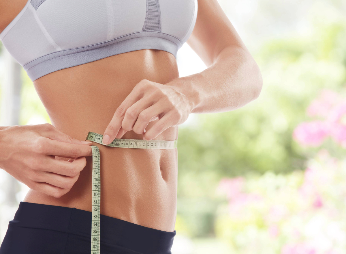 fitness woman measuring waistline, concept of waist-slimming exercises