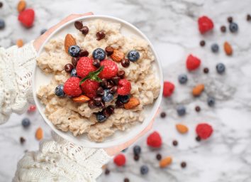 close-up holding bowl of oatmeal with berries, concept if eating oatmeal can make you gain weight