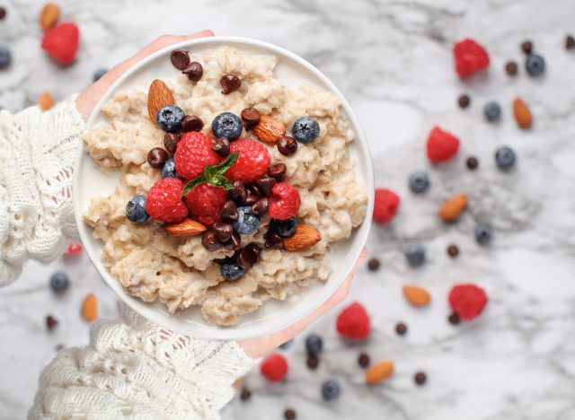close-up holding bowl of oatmeal with berries, concept if eating oatmeal can make you gain weight