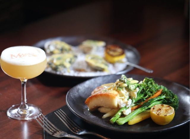 mccormick and schmick's salmon risotto on a table beside a festive cocktail and a plate of oysters