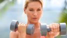 middle-aged woman doing dumbbell exercise outdoors, concept of free weight workouts to regain muscle mass