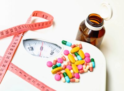 concept of weight-loss supplements with scale and tape measure