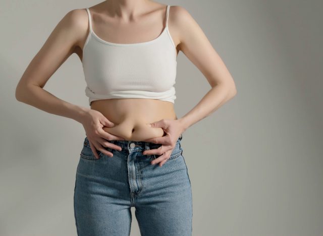 woman holding belly fat, concept of worst habits for belly fat