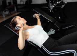 woman doing incline dumbbell bench press, concept of superset workouts for weight loss