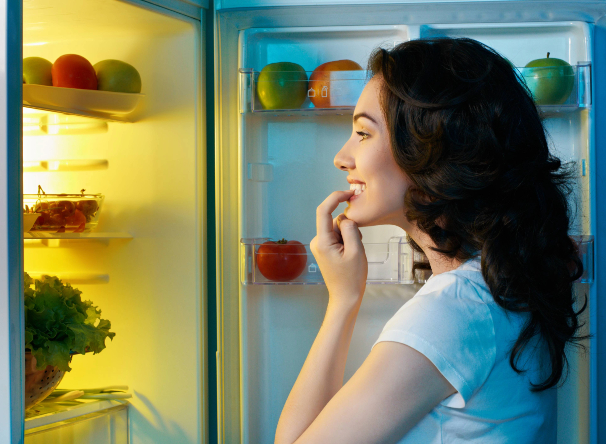 woman opens and looks into fridge, concept of the best snack to lose belly fat