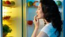 woman opens and looks into fridge, concept of the best snack to lose belly fat