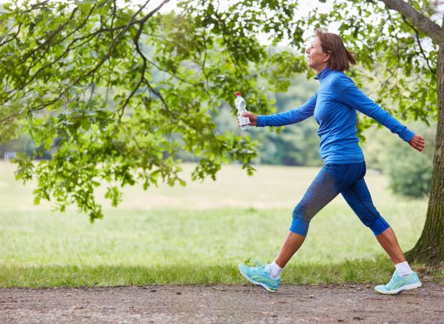 mature woman on brisk walk on trails, concept of low-impact exercises to melt belly fat