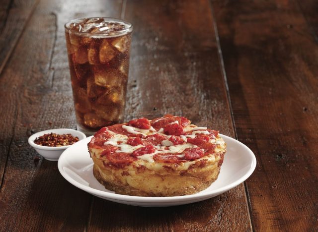 BJ's Mini Deep Dish pizza on a plate next to a cup of soda