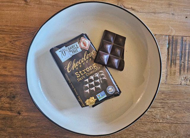 A package of Chocolove Strong Dark Chocolate next to a piece of chocolate on a white plate