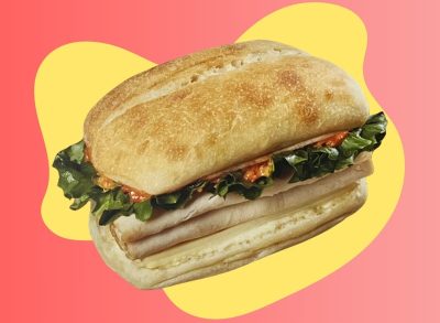 Costco's new food court turkey Swiss sandwich against a colorful background