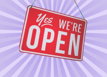 red "yes we're open sign" on lavender background