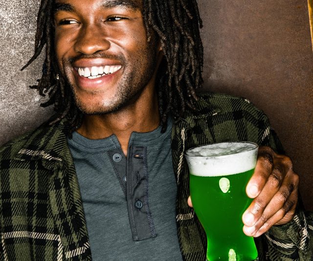 Happy customer drinking green-colored beer on St. Patrick's Day at Yard House restaurant