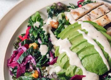 plate of kale salad with avocado and chicken