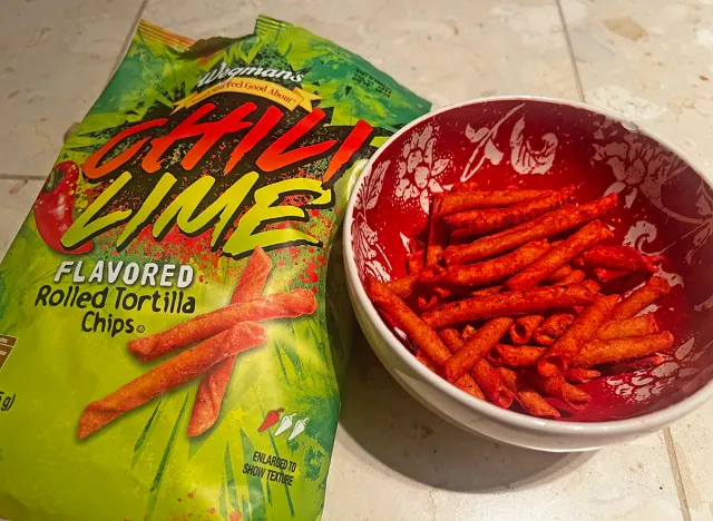 Wegmans chili lime rolled tortilla chips in a bowl beside the packaging