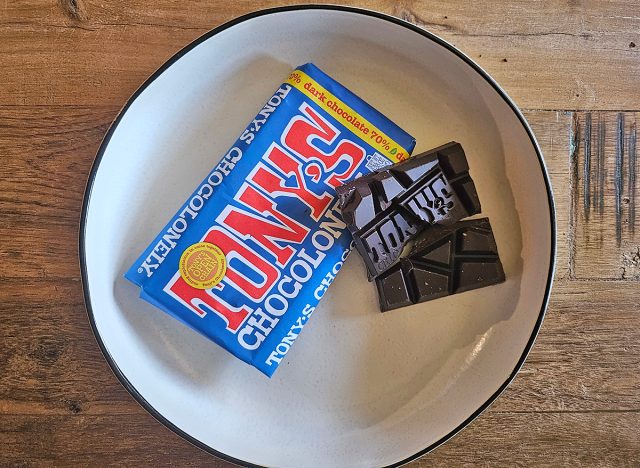 A package of Tony's Chocolonely next to a piece of dark chocolate on a white plate