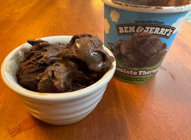 a container of ben and jerry's ice cream open on a table with a bowl of ice cream.