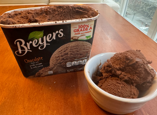 breyers chocolate ice cream in an open container and a bowl on a table. 