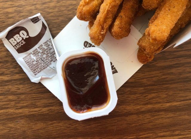 a packet of burger king bbq sauce with chicken fries on a table.