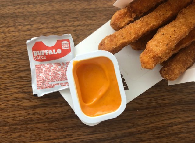 a packet of burger king buffalo sauce with chicken fries on a table.