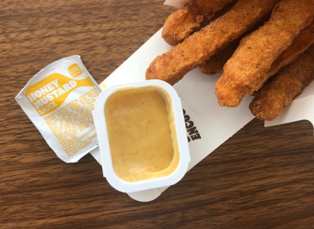 a packet of burger king honey mustard with chicken fries on a table.