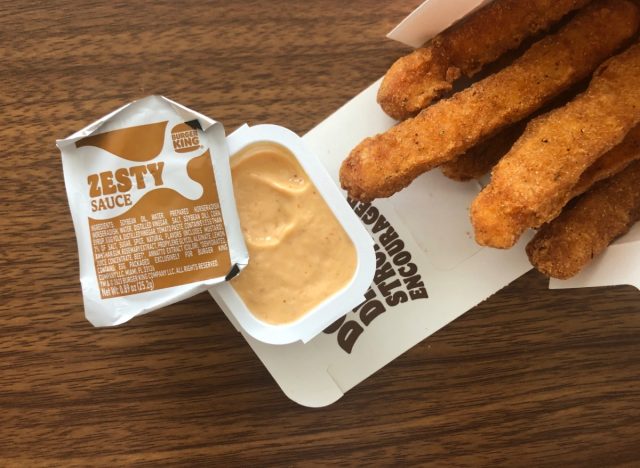 a packet of burger king zesty sauce with chicken fries on a table.