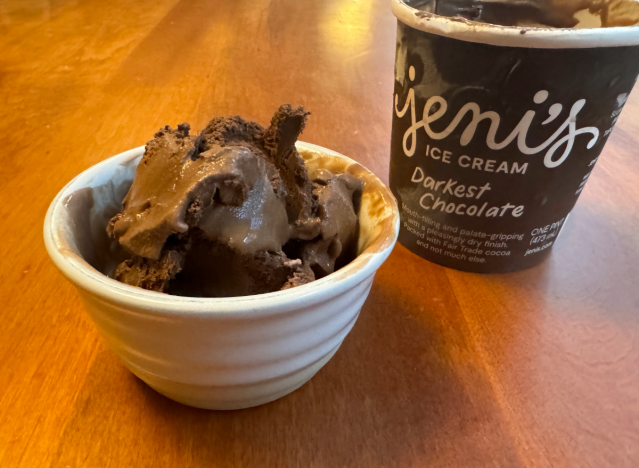 jeni's chocolate ice cream container open on a table with a bowl of ice cream.