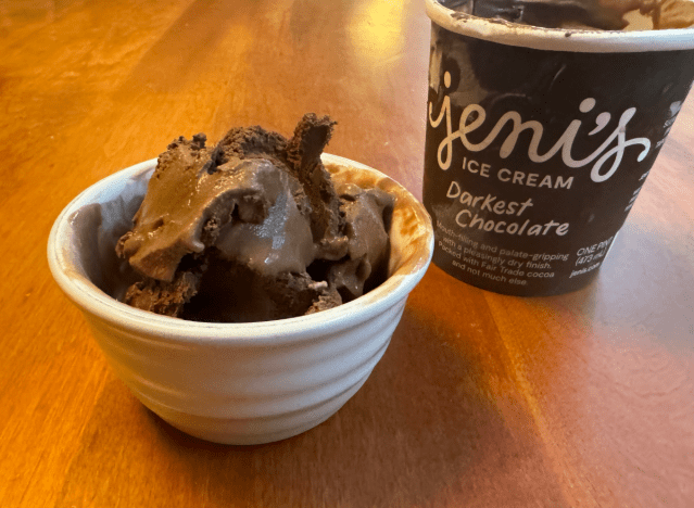 jeni's chocolate ice cream container open on a table with a bowl of ice cream.