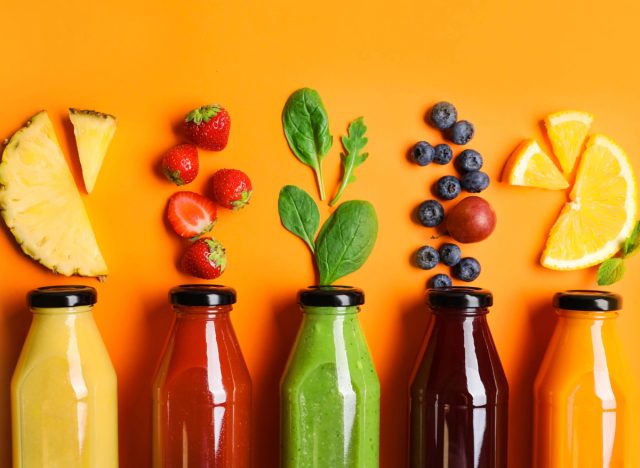 juice cleanse bottles on orange background with fruit