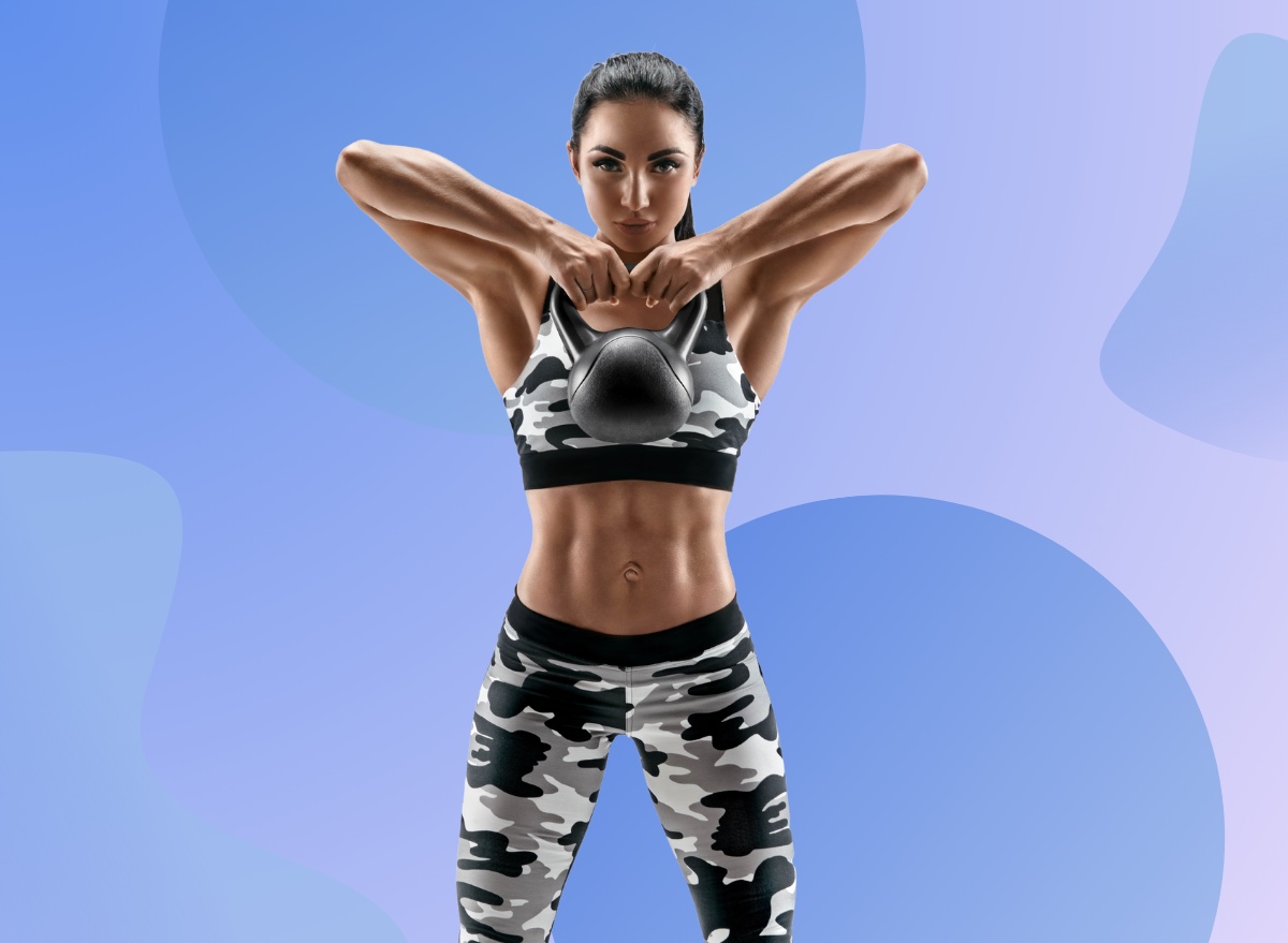 woman in camo sports bra and leggings doing a kettlebell high pull exercise in front of funky blue and purple backdrop