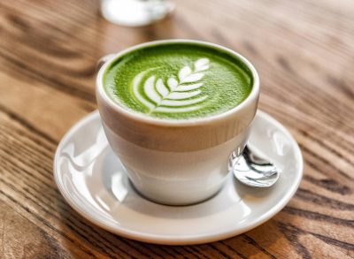 matcha latte with decorative foam on a wood table