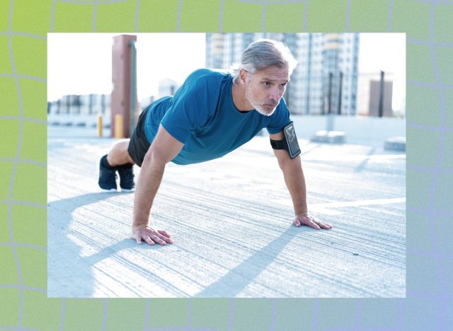mature, focused grey-haired man in blue t-shirt doing pushups on rooftop