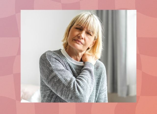 mature blonde woman in gray sweater dealing with joint/neck pain at home