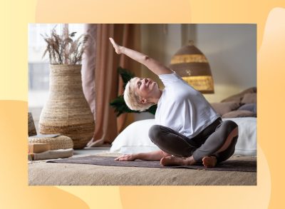 mature woman with short blonde hair stretching in boho bedroom on yoga mat