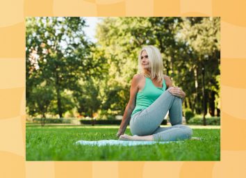 mature blonde woman stretching on blue yoga mat on grass, surrounded by trees and sunshine